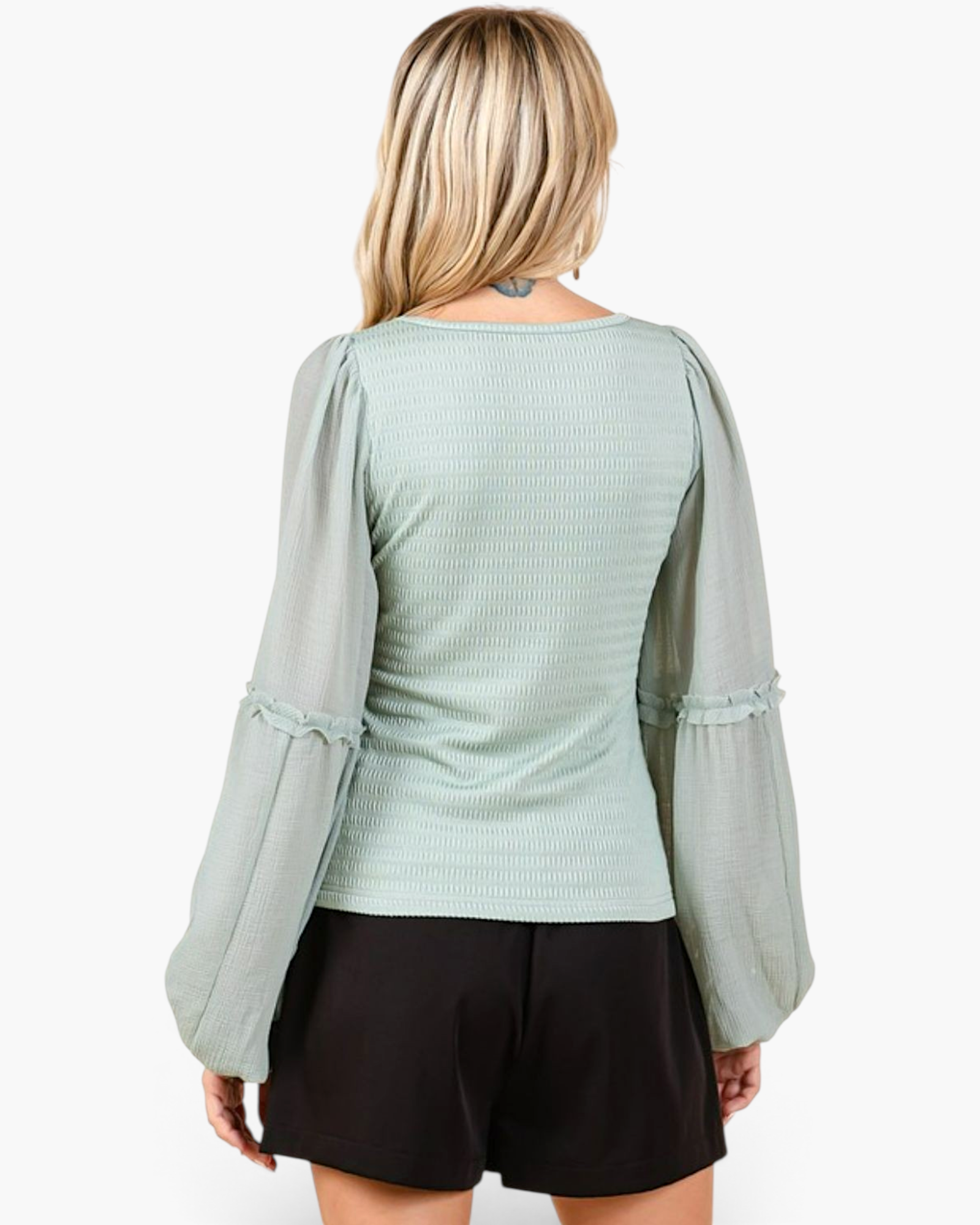 Back view of a Beach Rose Co. sage smocked chiffon blouse with sheer balloon sleeves and ruffle trim on a blonde model