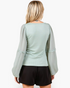 Back view of a Beach Rose Co. sage smocked chiffon blouse with sheer balloon sleeves and ruffle trim on a blonde model