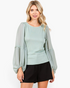 Beach Rose Co. sage green smocked chiffon blouse with sheer balloon sleeves and ruffle trim on a blonde model