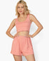 Beach Rose Co. model wearing a salmon pink textured crop tank top and matching elastic waist shorts set.