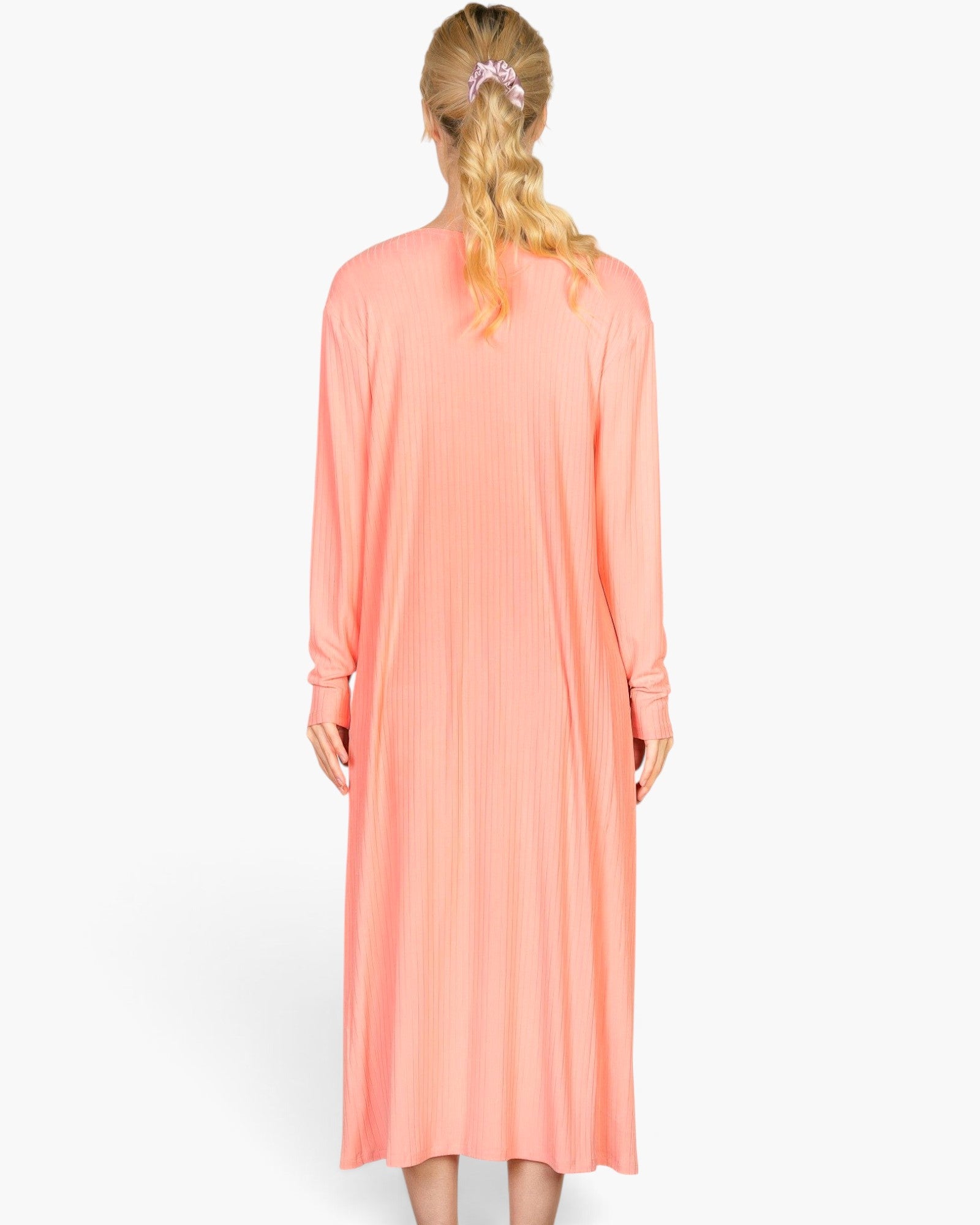 Back view of a model wearing a salmon-colored Beach Rose Co. ribbed long-sleeve cardigan over a matching midi dress.