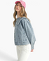 Beach Rose Co. light wash denim jacket with an oversized scalloped collar worn by a model in a pink baseball cap.