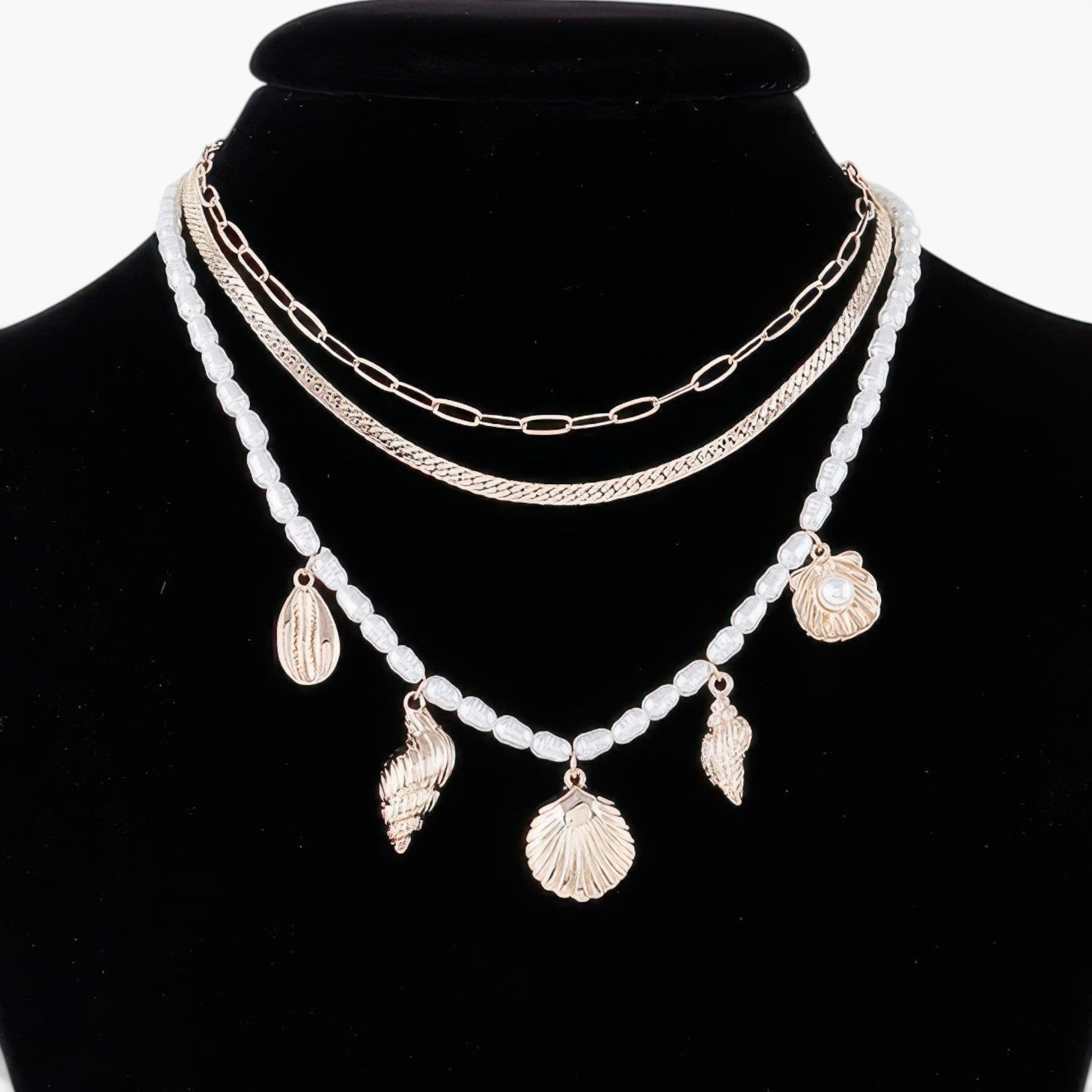 Beach Rose Co. multi-layered necklace with gold chains, white pearls, and dangling gold seashell charms on a bust.