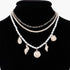 Beach Rose Co. multi-layered necklace with gold chains, white pearls, and dangling gold seashell charms on a bust.