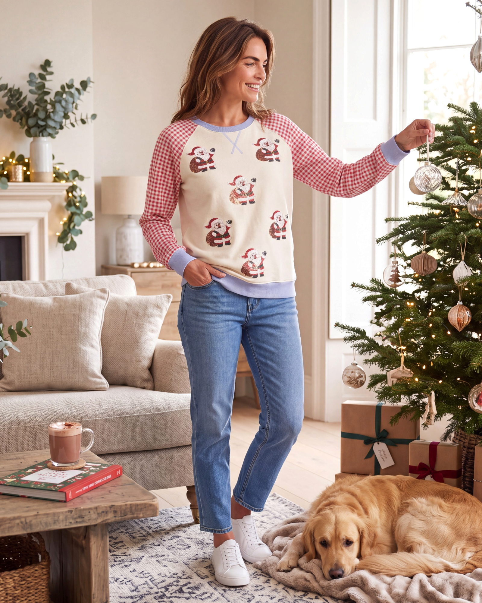 Beach Rose Co. cream sweatshirt with sequin Santa motifs and red gingham raglan sleeves worn by a woman decorating.