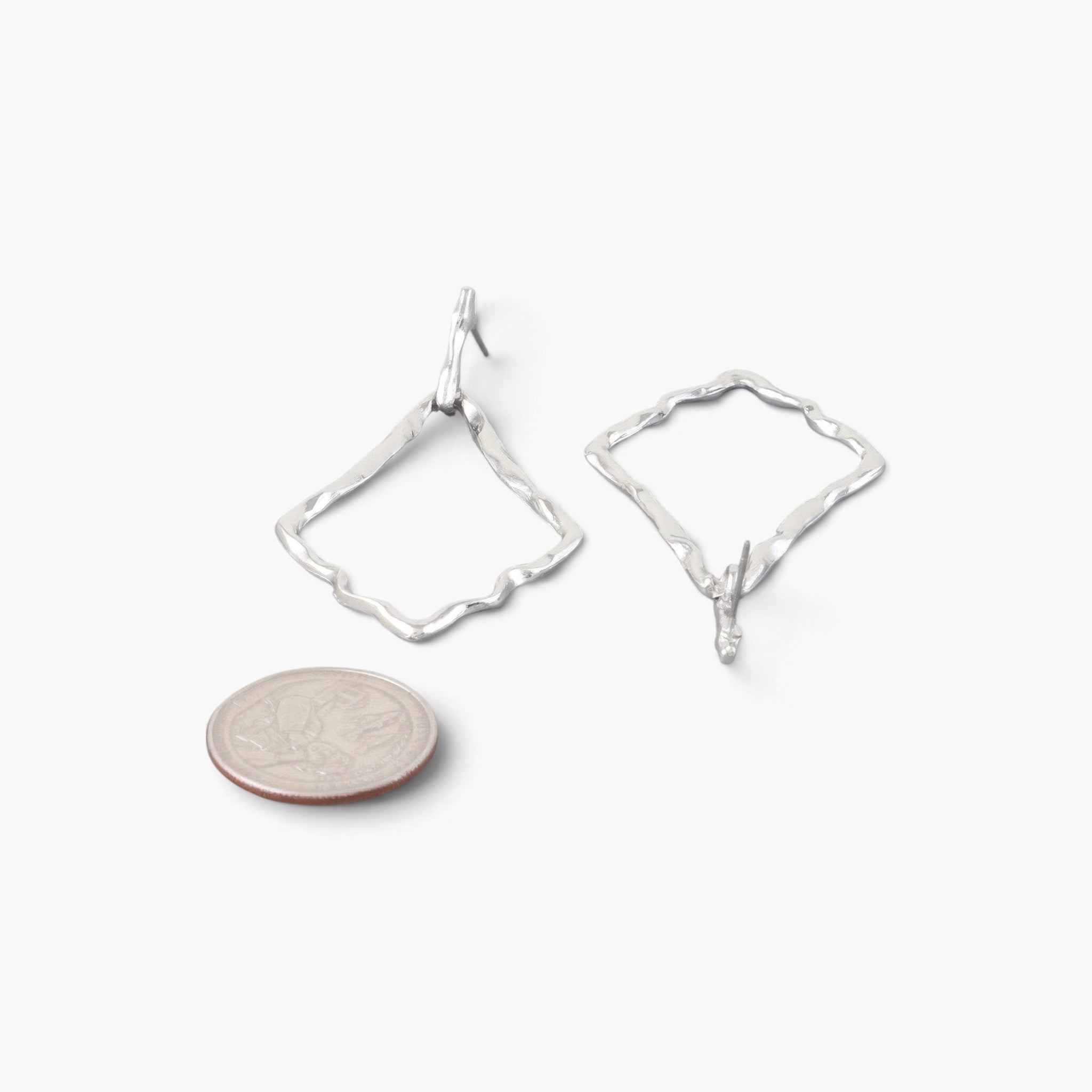 Beach Rose Co. silver-tone hammered kite earrings with a textured finish next to a US quarter for size reference.