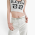 Beach Rose Co. slim silver metal waist belt with an intricate interwoven knot buckle worn over white jeans