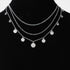 Beach Rose Co. silver triple layered chain necklace featuring delicate round charms on a black display bust.