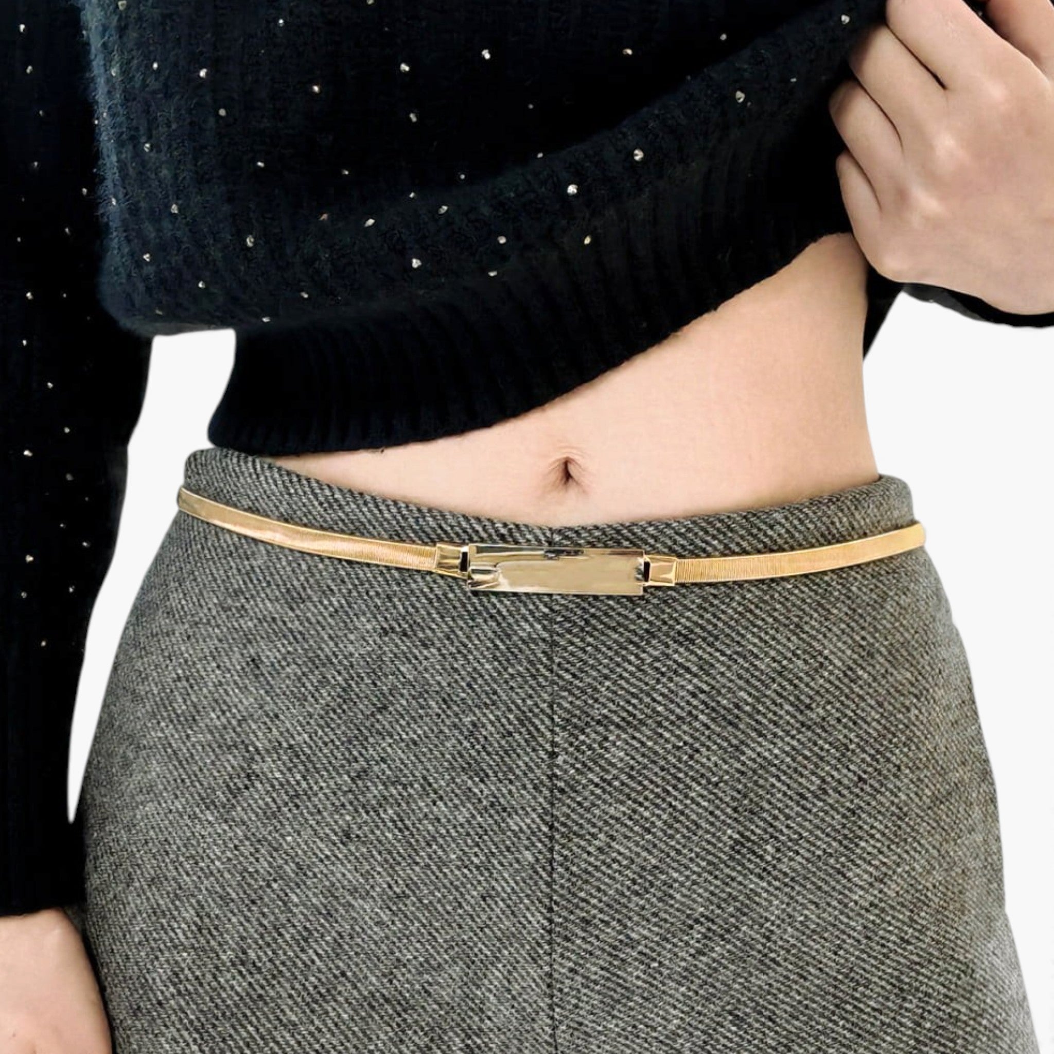 Beach Rose Co. slim gold-tone iron waist belt with a polished rectangular clasp worn over grey wool trousers