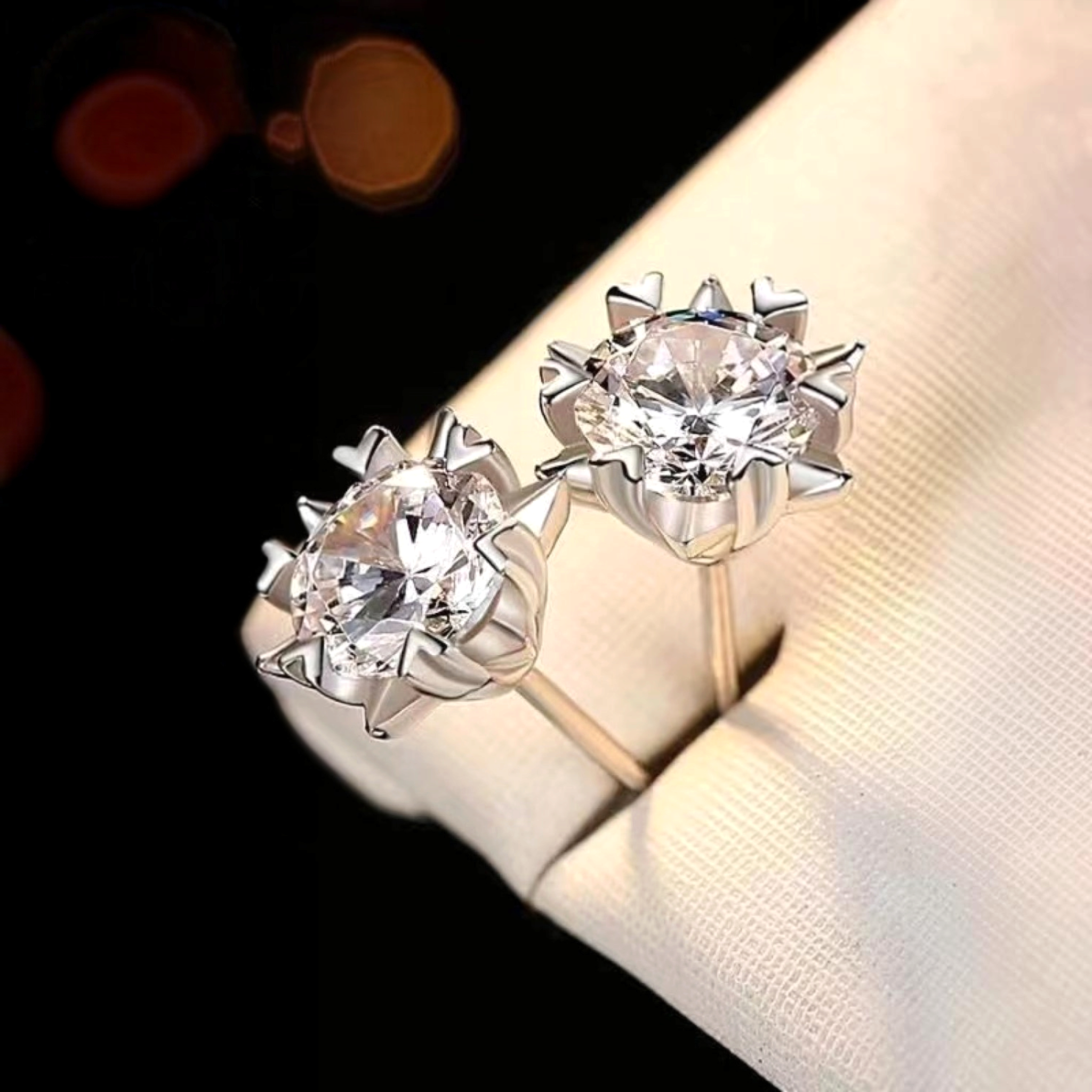 Beach Rose Co. silver starburst moissanite stud earrings with heart-shaped prongs and 4 carat total weight.