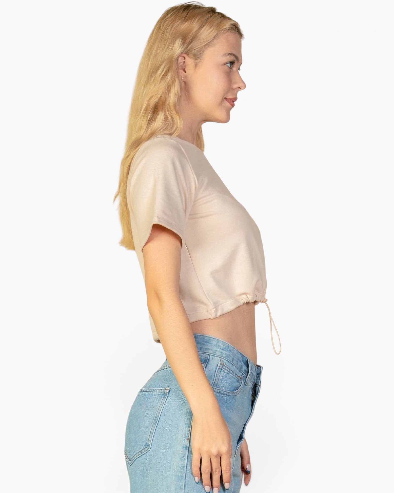 Beach Rose Co. stone-colored French Terry crop top with a toggle drawstring hem worn by a blonde model in profile.