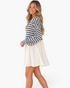 Beach Rose Co. navy and ivory striped babydoll mini dress with billowy sleeves worn by a smiling blonde model.