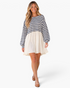 Beach Rose Co. navy and ivory striped babydoll mini dress with long billowy sleeves worn by a smiling blonde model