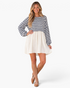 Beach Rose Co. navy and ivory striped babydoll mini dress with long billowy sleeves worn by a smiling blonde model.
