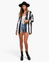 Model wearing Beach Rose Co. black and white striped button-up shirt with dropped shoulders, shorts, and black hat.