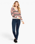 Beach Rose Co. model wearing a multi-colored variegated striped v-neck knit sweater with ruffled hem and dark jeans.