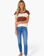 Beach Rose Co. rust and ivory striped open-knit top with a split neckline and cap sleeves worn with blue jeans.