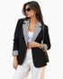 Beach Rose Co. black blazer with white striped notched lapels and turn-back cuffs worn by a woman in sunglasses.