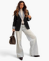 Beach Rose Co. black blazer with white striped lapels and cuffs worn by a woman with light wash wide-leg jeans