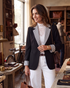 Beach Rose Co. black blazer with white striped lapels and cuffs worn by a woman in a boutique setting.