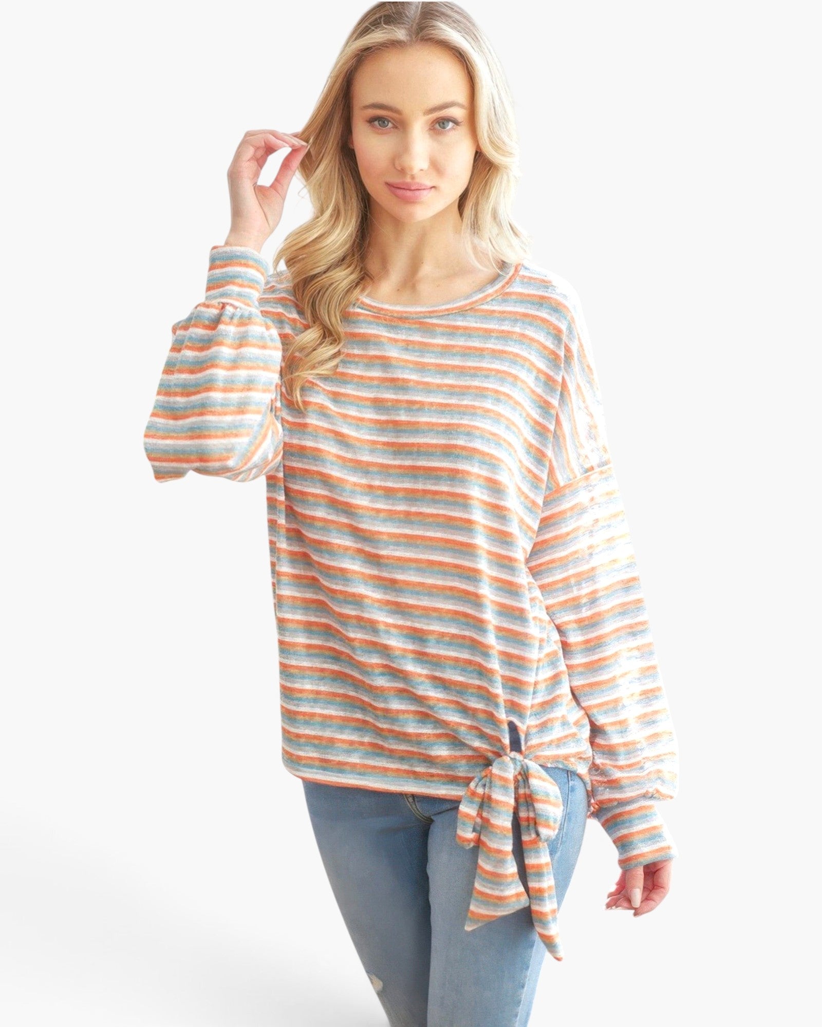 Beach Rose Co. model wearing a soft orange and blue tri-tone striped long sleeve top with a front tie ribbon detail.