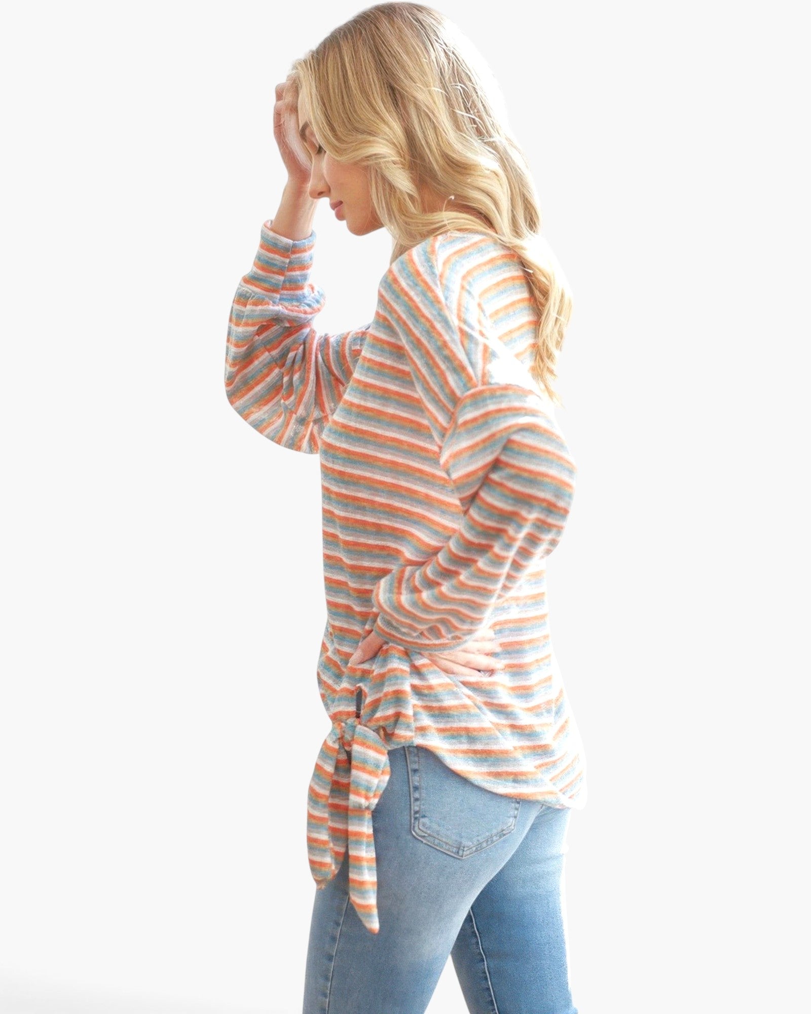 Beach Rose Co. model wearing an orange tri-tone striped long sleeve top with a self-tie ribbon detail and blue jeans.