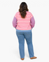 Beach Rose Co. pink and cream striped sweatshirt with blue sleeves and relaxed fit worn with blue jeans, back view.