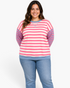 Beach Rose Co. model wearing a relaxed pink and cream striped sweatshirt with blue sleeves and crew neck trim.