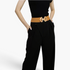 Beach Rose Co. tan elastic waist belt with a gold geometric double diamond alloy buckle worn over black trousers.