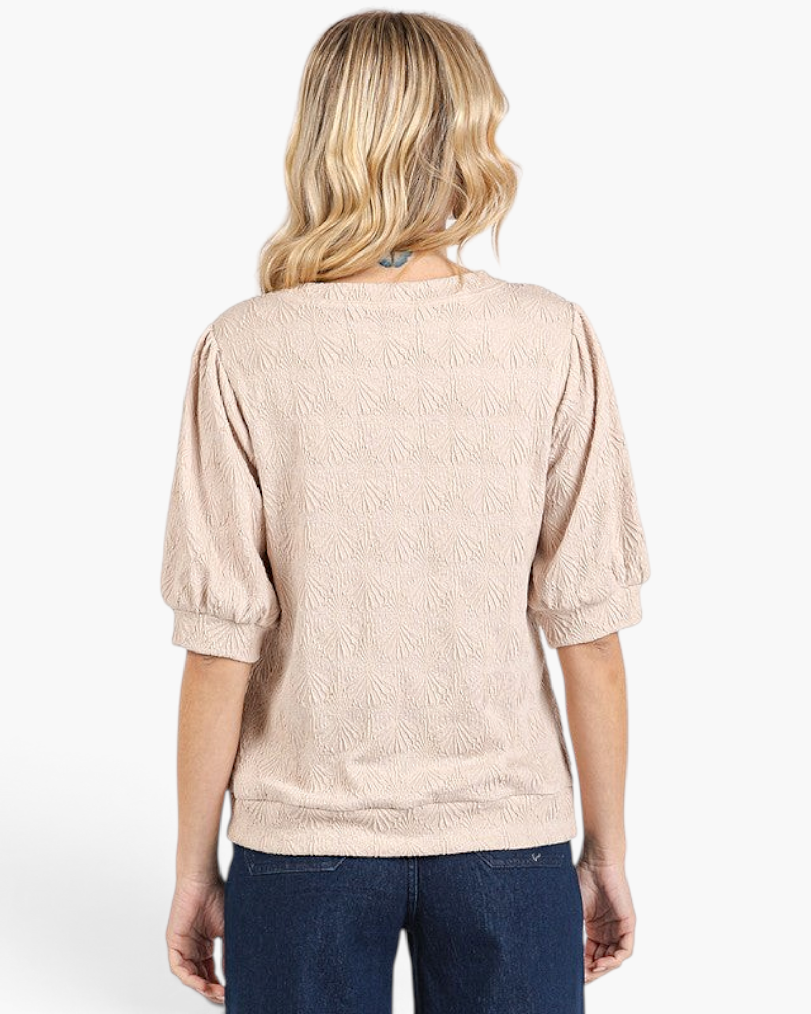 Back view of Beach Rose Co. tan textured top with puff sleeves and banded hem worn with blue jeans