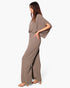 Model wearing a Beach Rose Co. taupe textured mock neck caftan jumpsuit with wide sleeves and a flowing silhouette.