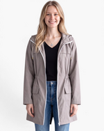 Beach Rose Co. taupe waterproof hooded rain jacket with a zip-front, flap pockets, and gathered waist on a model.