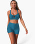 Beach Rose Co. teal two-piece bikini with a crisscross top and high-waisted tummy control shorts on a model.