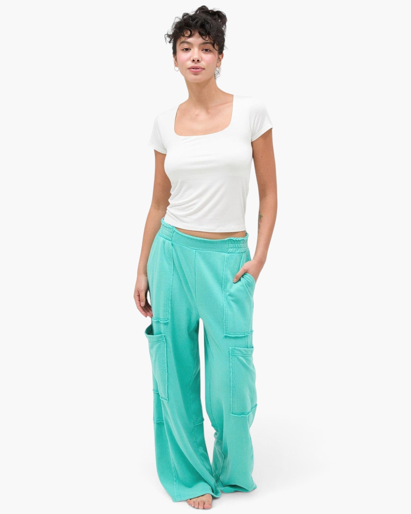 Beach Rose Co. mineral wash wide leg cargo pants in teal cotton with raw edge pockets worn by a model