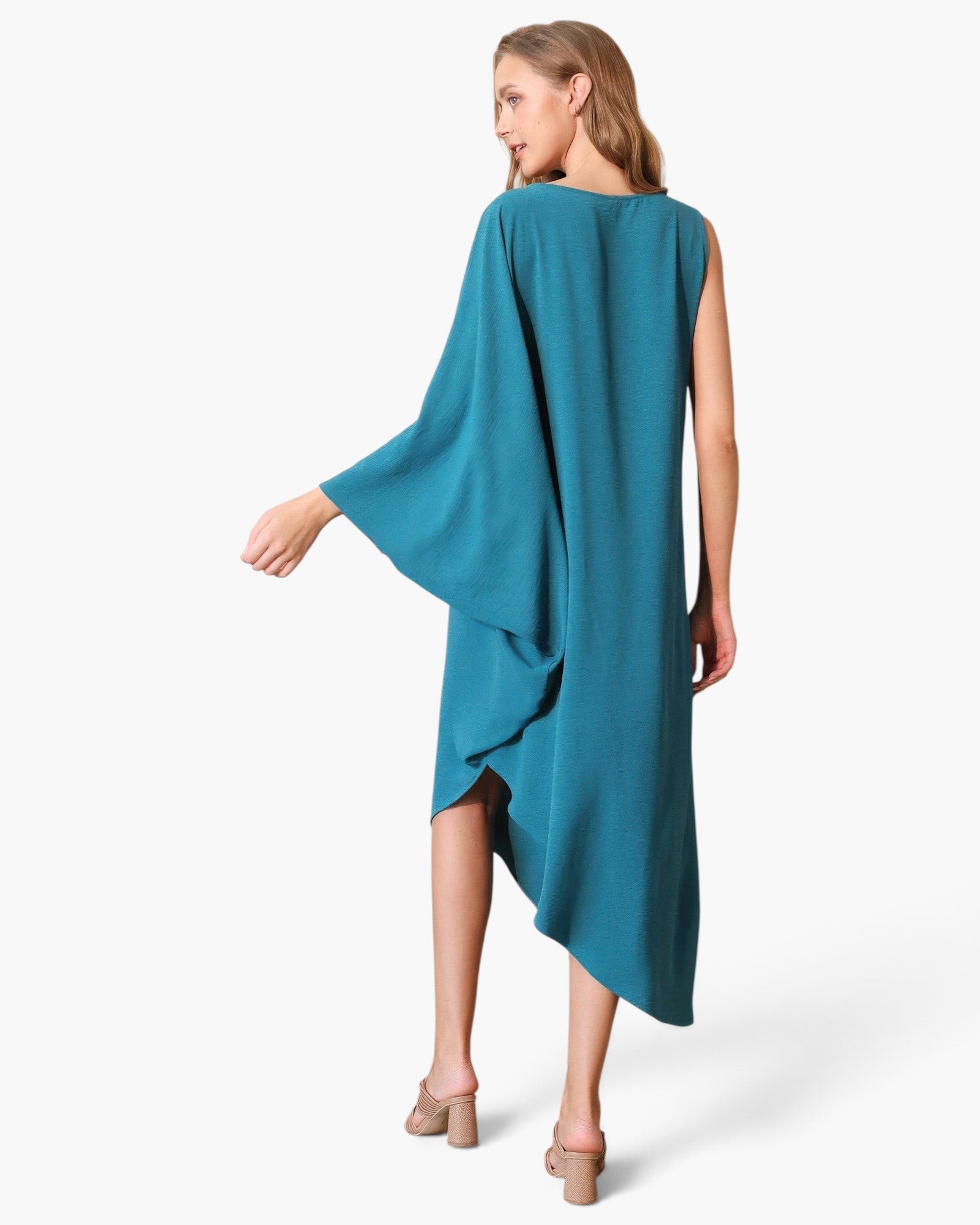 Beach Rose Co. teal matte crepe one-sleeve dress with an asymmetrical hem worn by a model in a studio setting.