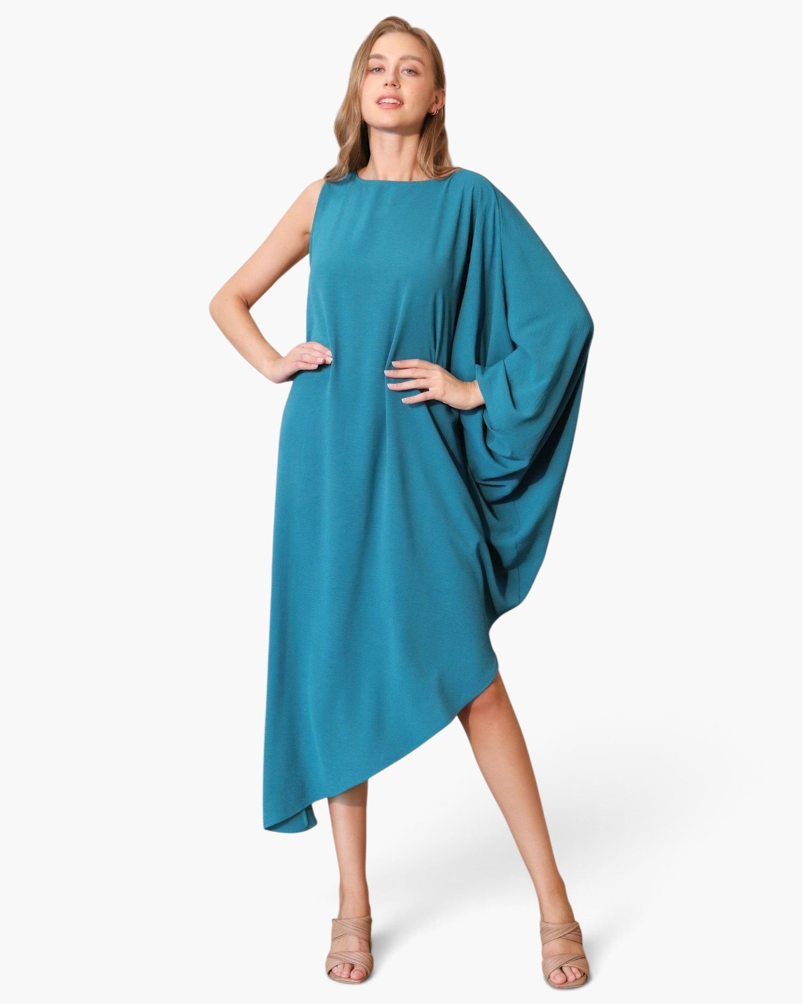 Beach Rose Co. teal matte crepe one-sleeve dress with an asymmetrical hem worn by a model in a studio setting