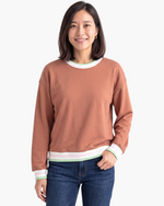 Beach Rose Co. terracotta crewneck sweatshirt with striped trim on the neckline, cuffs, and hem worn by a woman.