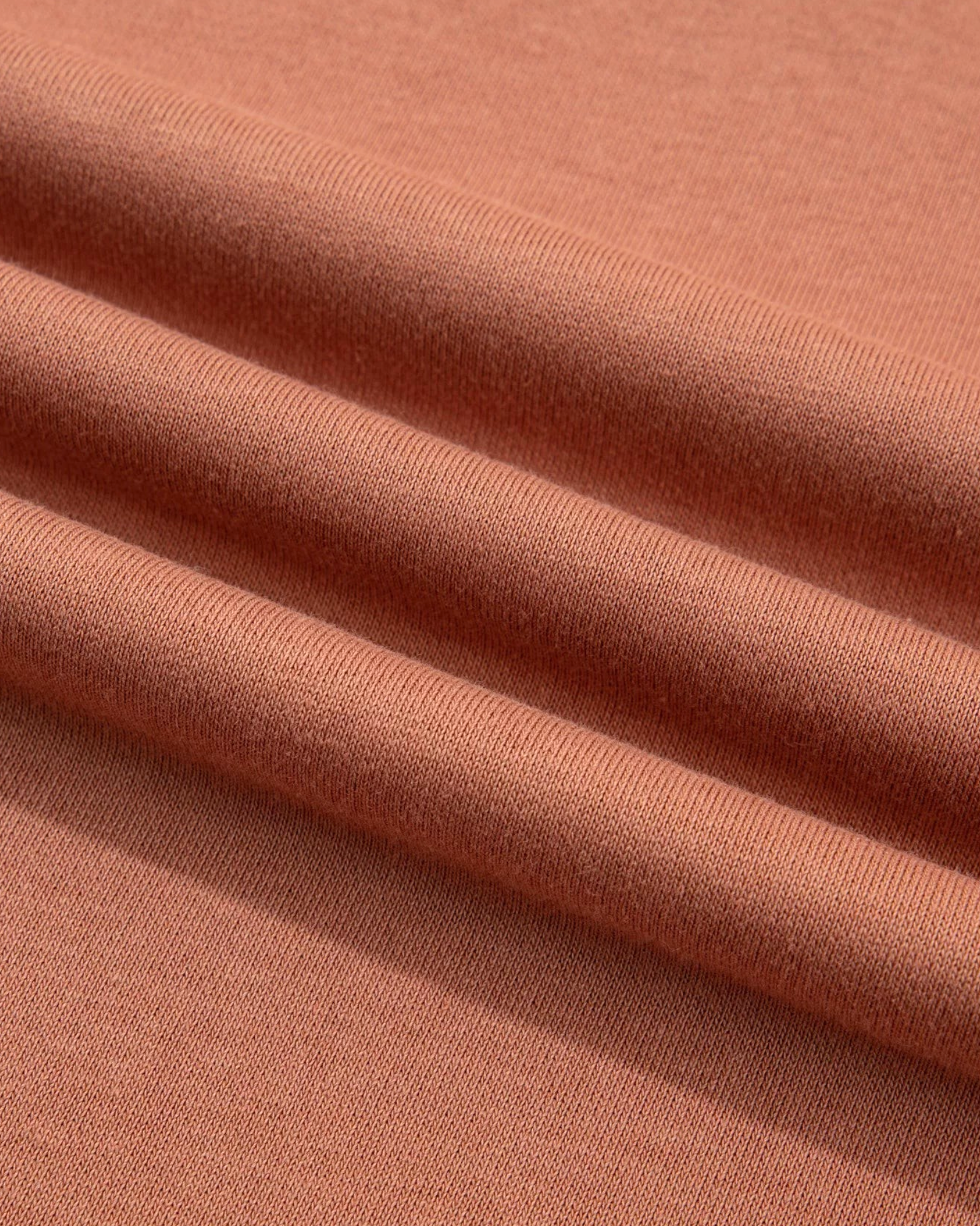 Close-up of Beach Rose Co. sweatshirt fabric in a soft terracotta colour showing the smooth cotton-polyester texture