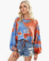 Beach Rose Co. model wearing a round neck tie-dye top with long balloon sleeves in blue and orange polyester fabric.