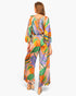 Back view of a model wearing a Beach Rose Co. satin jumpsuit with a vibrant tropical print and blouson bodice.
