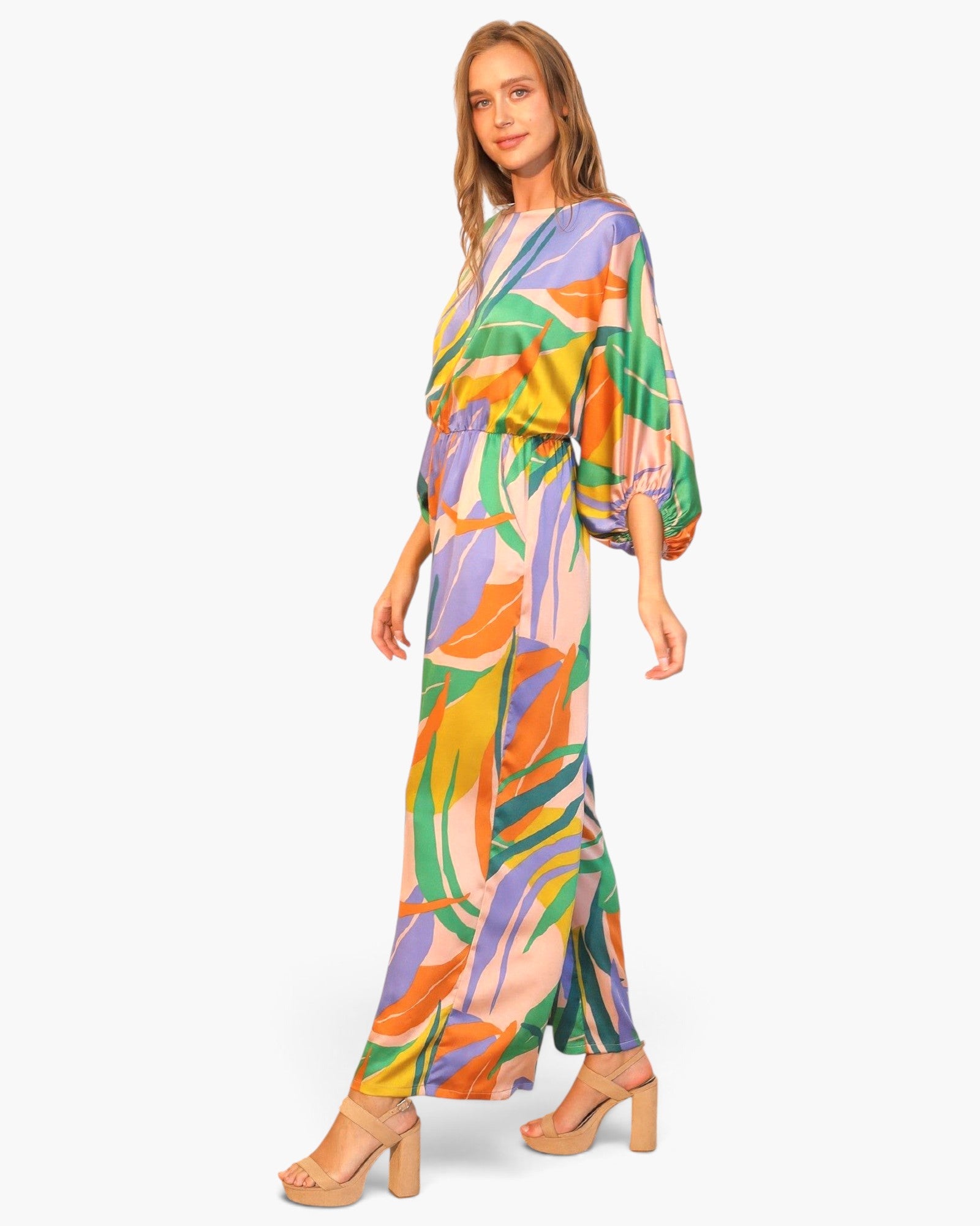 Beach Rose Co. Isla Tropical satin jumpsuit with boat neck, blouson bodice, and vibrant leaf print on a model