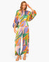 Model wearing Beach Rose Co. Isla Tropical satin jumpsuit with boat neck, blouson sleeves, and vibrant leaf print.