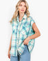 Model wearing a Beach Rose Co. turquoise plaid cotton button-front shirt with cap sleeves and raw hem detailing.