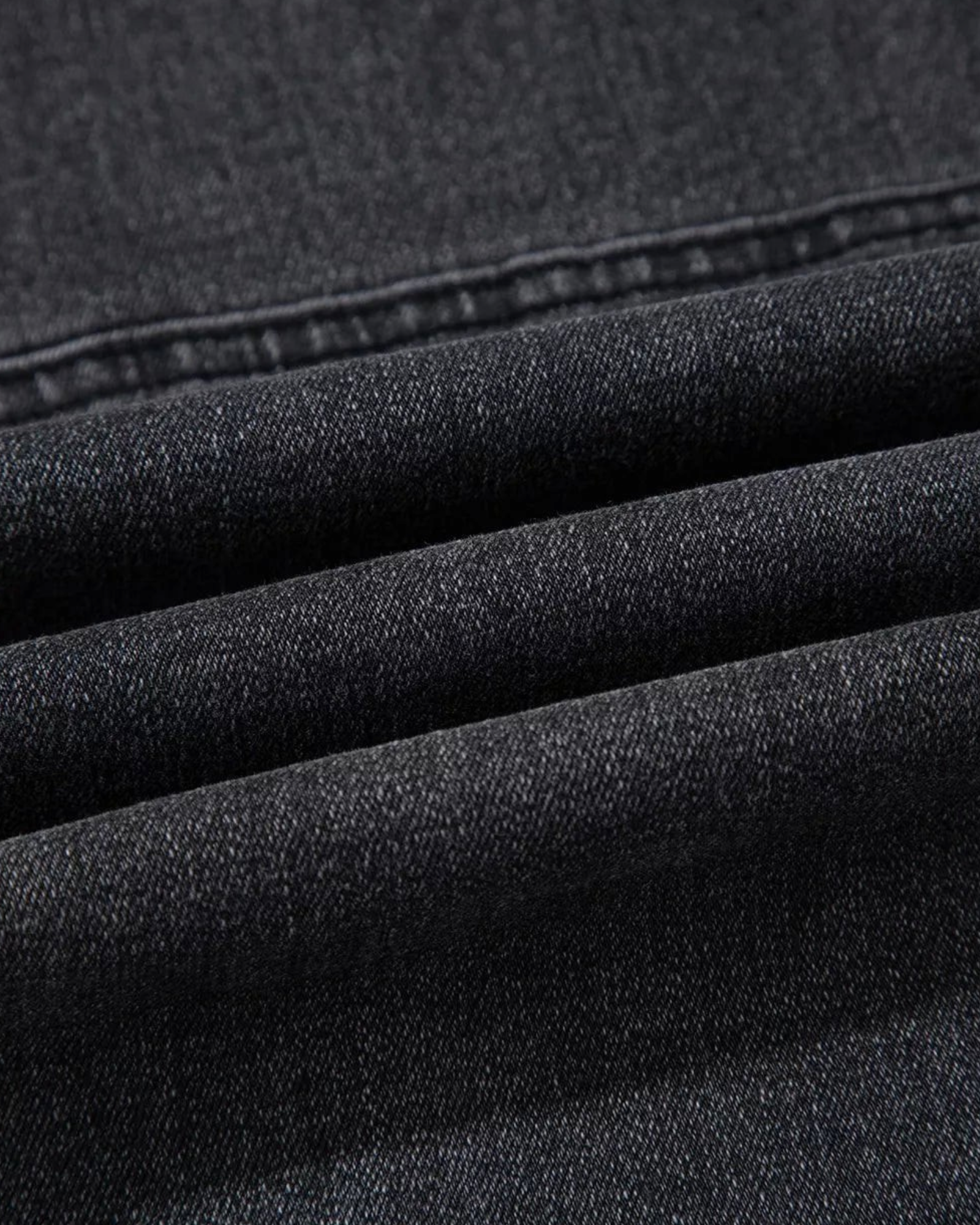 Close-up of Beach Rose Co. washed black cotton blend denim fabric with visible seam detailing and texture.