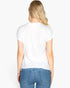 Back view of a blonde woman wearing a white Beach Rose Co. batwing sleeve tee with blue jeans