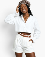 Beach Rose Co. white cropped blouse with balloon sleeves, smocked cuffs, and button front worn by a smiling model.