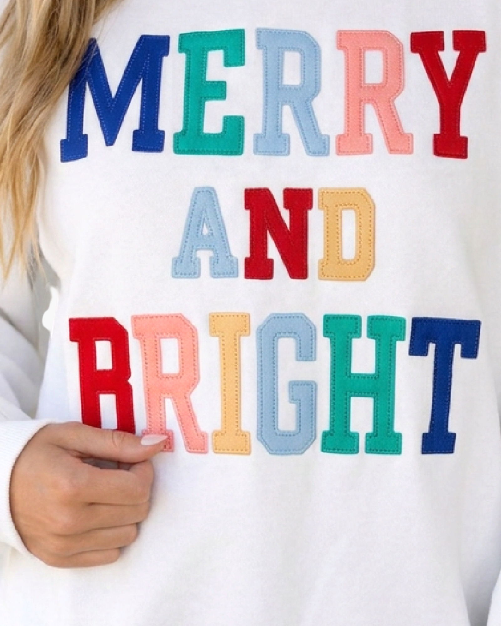Beach Rose Co. white sweatshirt featuring multicolored MERRY AND BRIGHT appliqué lettering with stitched detailing.