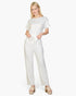 Beach Rose Co. white relaxed fit rib knit jumpsuit with a tie waist worn by a blonde model with platform sandals