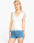 Beach Rose Co. white ribbed V-neck sleeveless jersey top worn by a blonde model with denim shorts