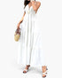 Beach Rose Co. white sleeveless maxi dress with a high waist, open back, and tiered skirt, styled with a straw bag.